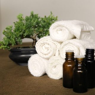 essential oil bottles with white towels and a potted plant in the background
