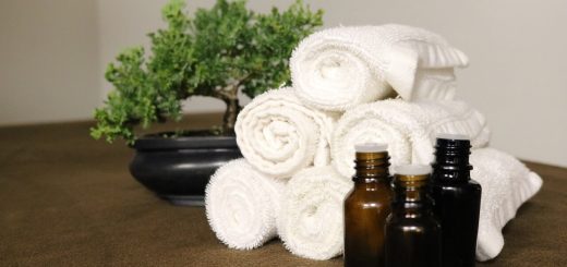 essential oil bottles with white towels and a potted plant in the background