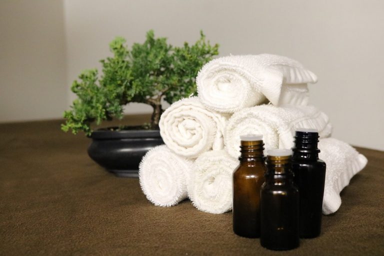 essential oil bottles with white towels and a potted plant in the background