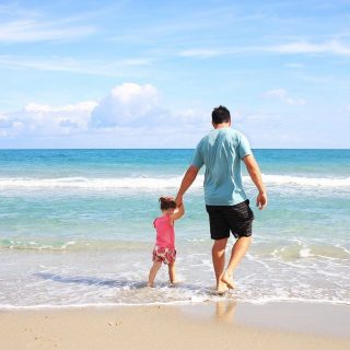 father and young daughter walking along the shoreline