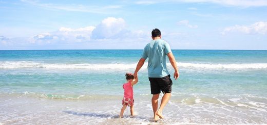 father and young daughter walking along the shoreline