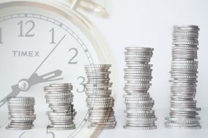stacks of coins in front of a clock