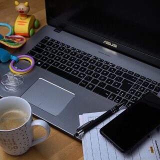 computer with toys, coffee and notes surrounding it