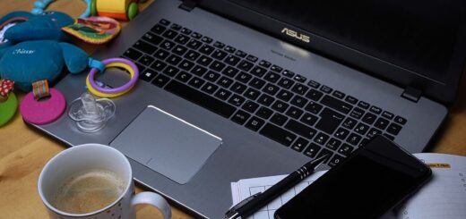 computer with toys, coffee and notes surrounding it